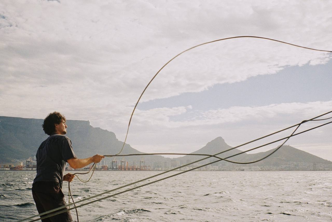 A crew member hauling a line with Table Mountain behind